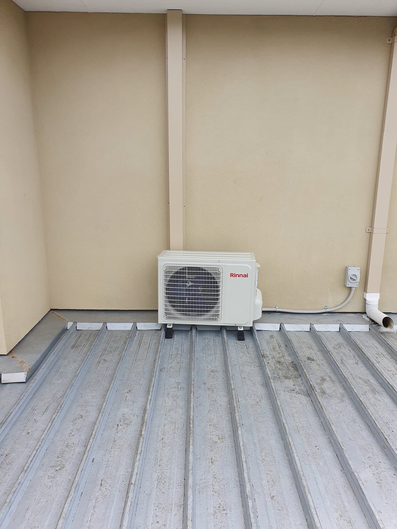 An outdoor condenser sat on mounting rails on a metal deck roof in Glenroy with a neat conduit and drain run to the wall outlet