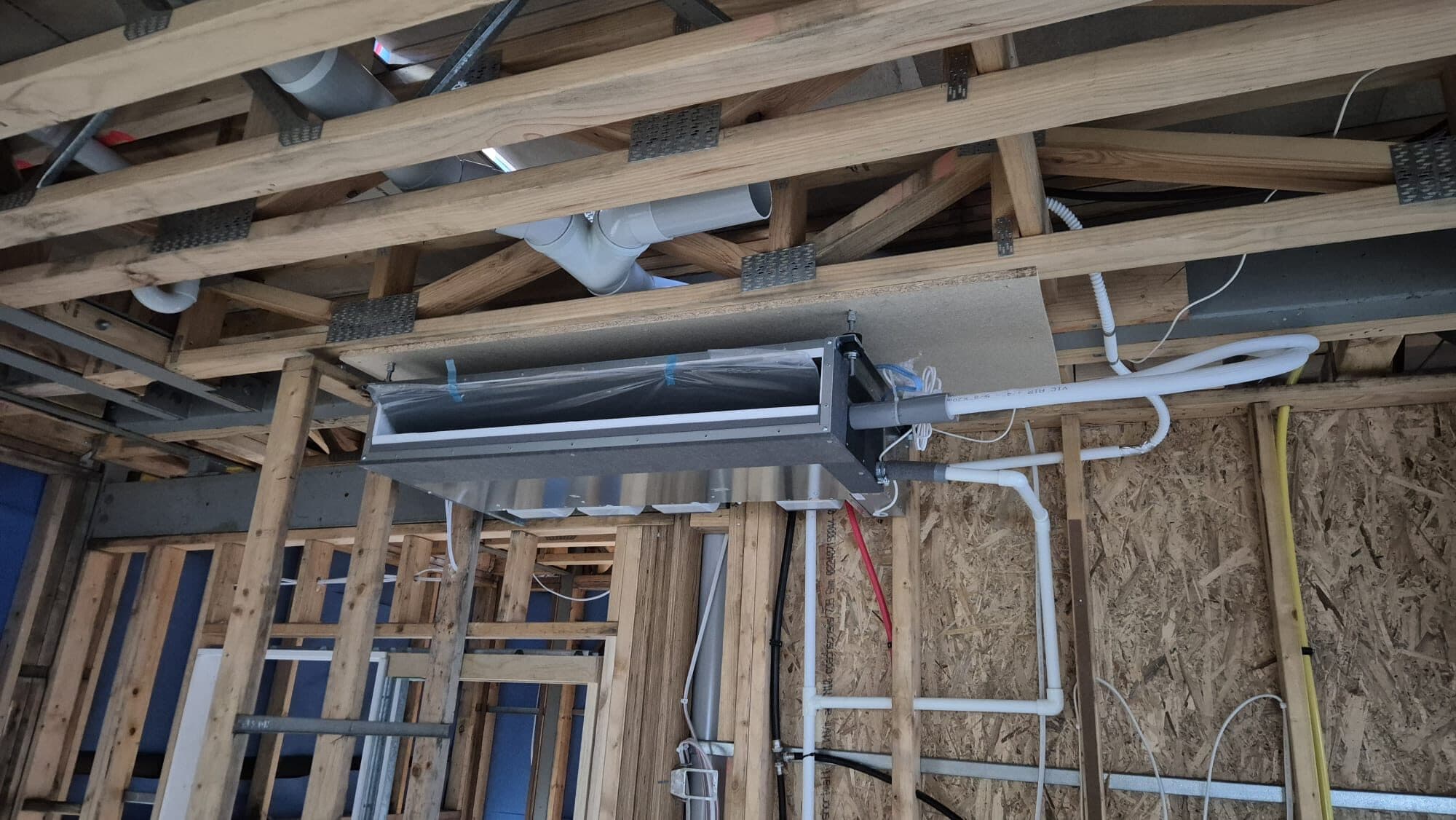 A bulkhead indoor unit slung in timber framing at Safety Beach with neat refrigerant pipe runs and ducting before fit-off