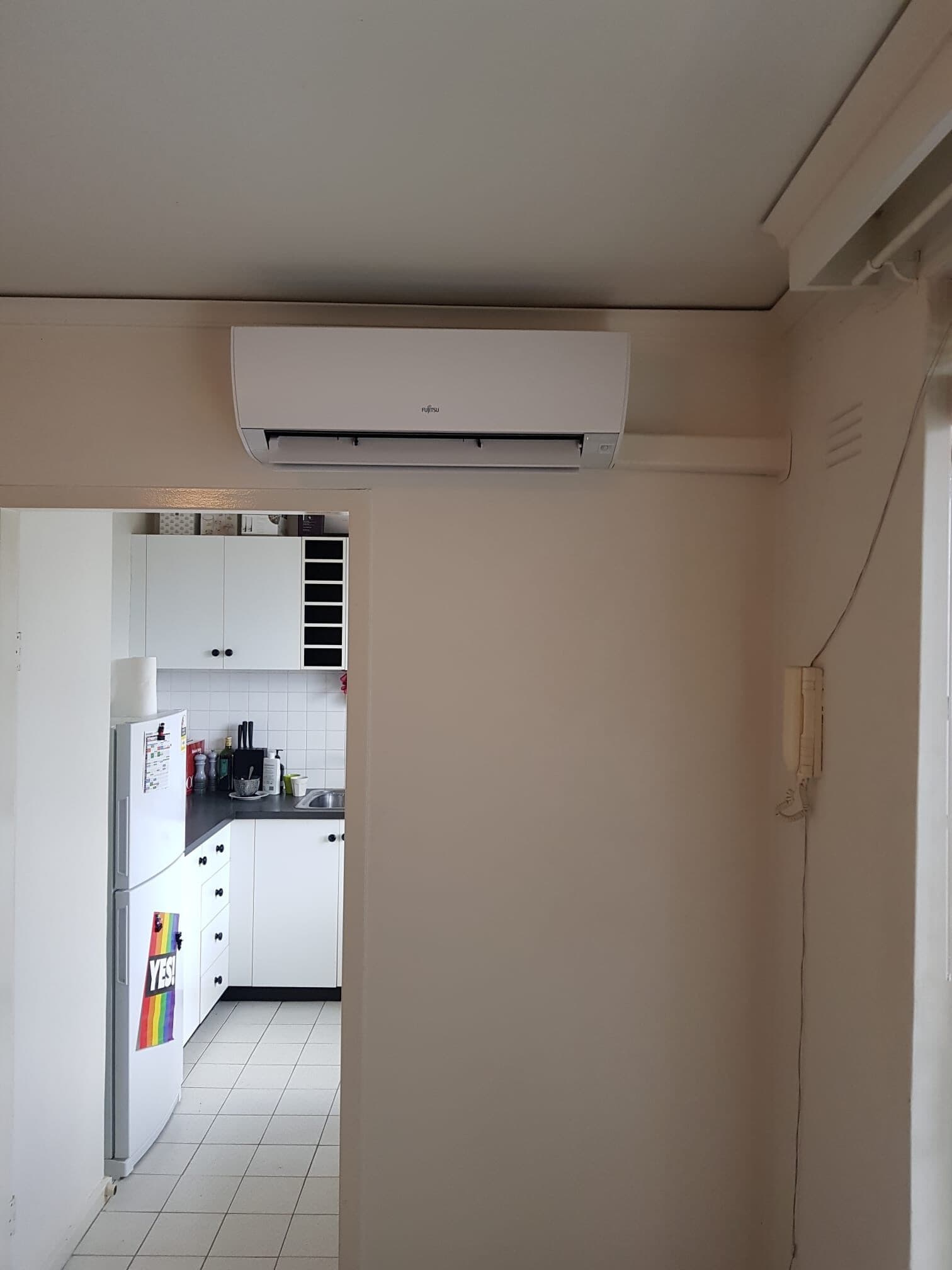 A wall-mounted split-system head with a tidy capped conduit run into an apartment in St Kilda
