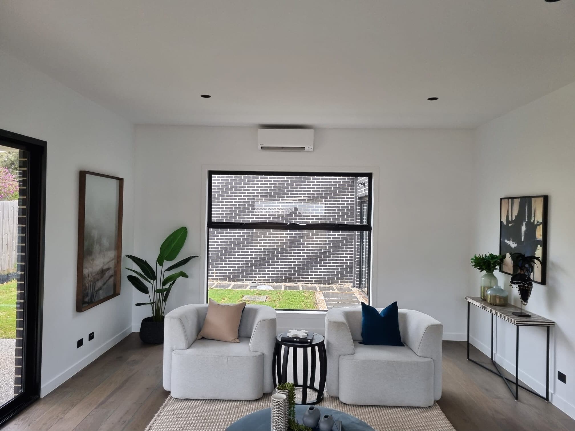 A wall-mounted split-system head above the window in a styled, light-filled living room in Wheelers Hill