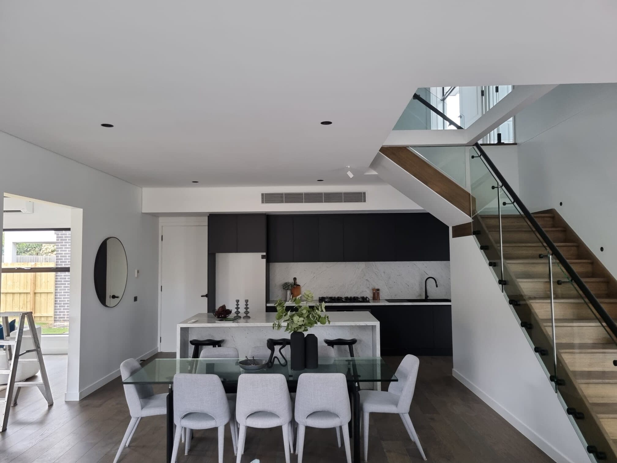 A ducted bulkhead grille set neatly above the cabinetry in an open-plan living and dining area of a Climate Group fit-off in Wheelers Hill