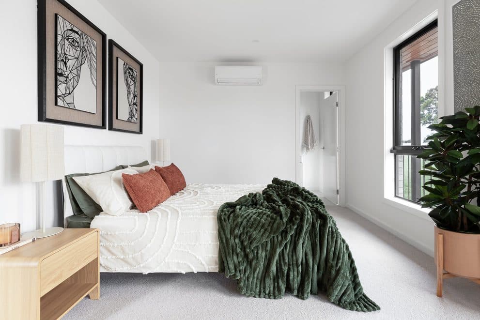 Wall-mounted split-system head installed above the bed in a Luma townhome bedroom