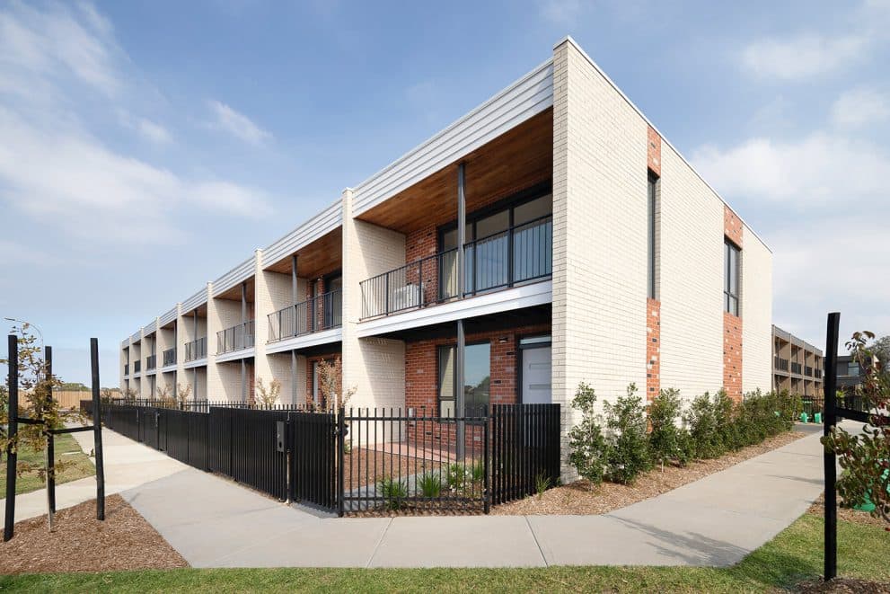 Corner view of the Luma townhomes in Sunshine North, showing the rendered facade and timber-lined balconies