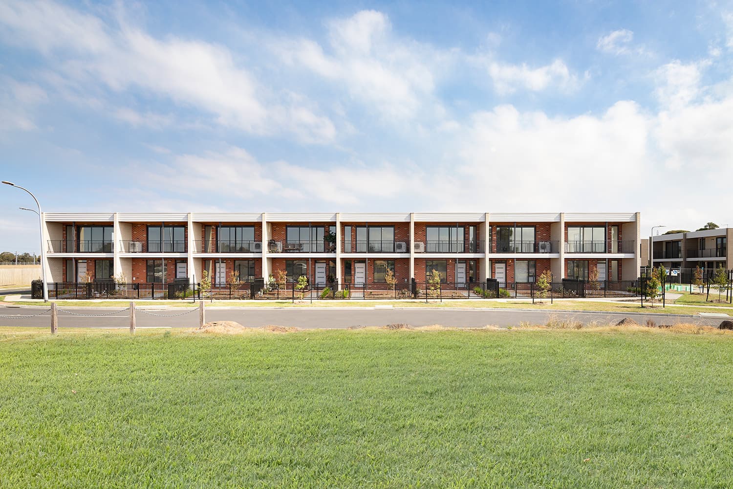 The Luma townhouse development, a row of two-storey homes seen from across the open parkland frontage